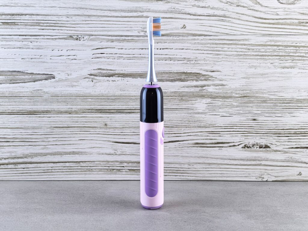 Purple electric toothbrush standing upright for oral hygiene dental care