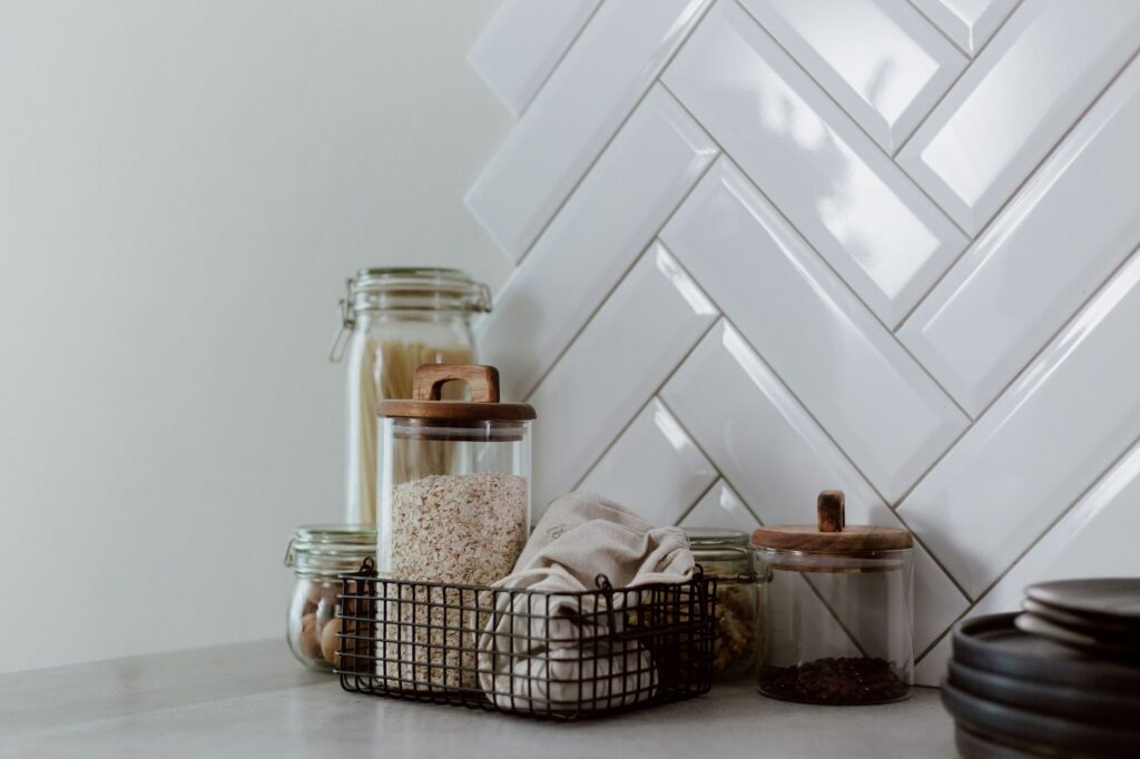 Glass food storage containers in kitchen with pasta and grains
