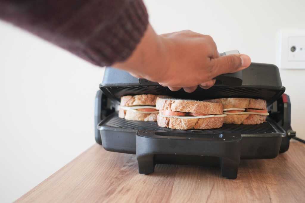 Electric sandwich maker grill in use for quick breakfast at home