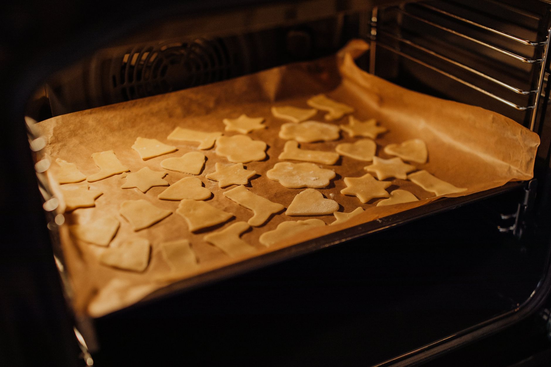 Cookies baking inside an OTG oven on a parchment-lined baking tray