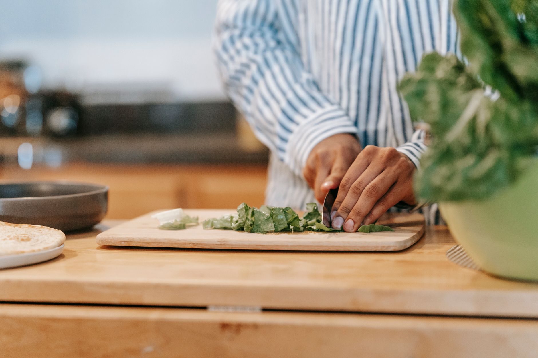 Man cutting fresh spinach on chopping board at home - vegetable chopper makes daily Indian cooking prep faster