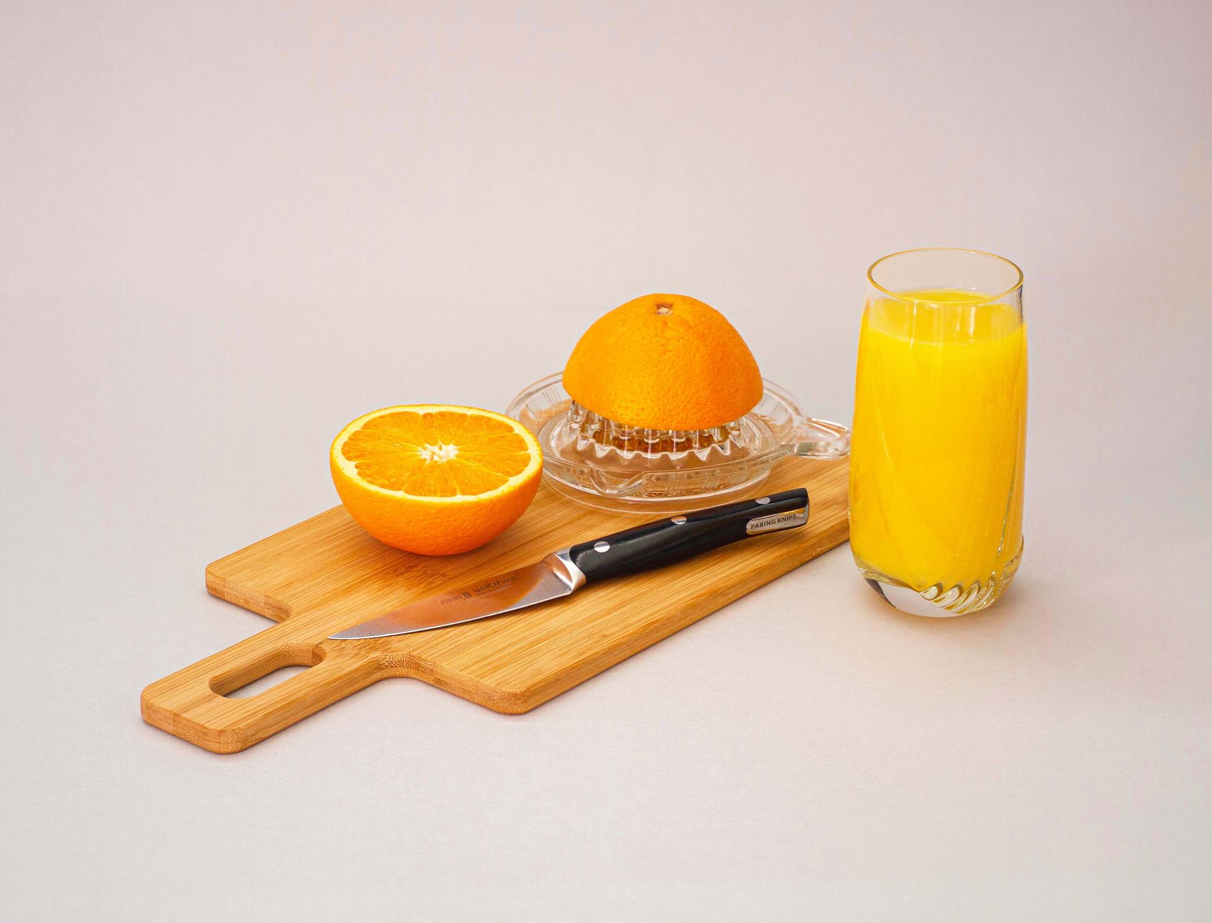 Fresh orange juice with sliced oranges and citrus juicer on wooden board — best juicers India