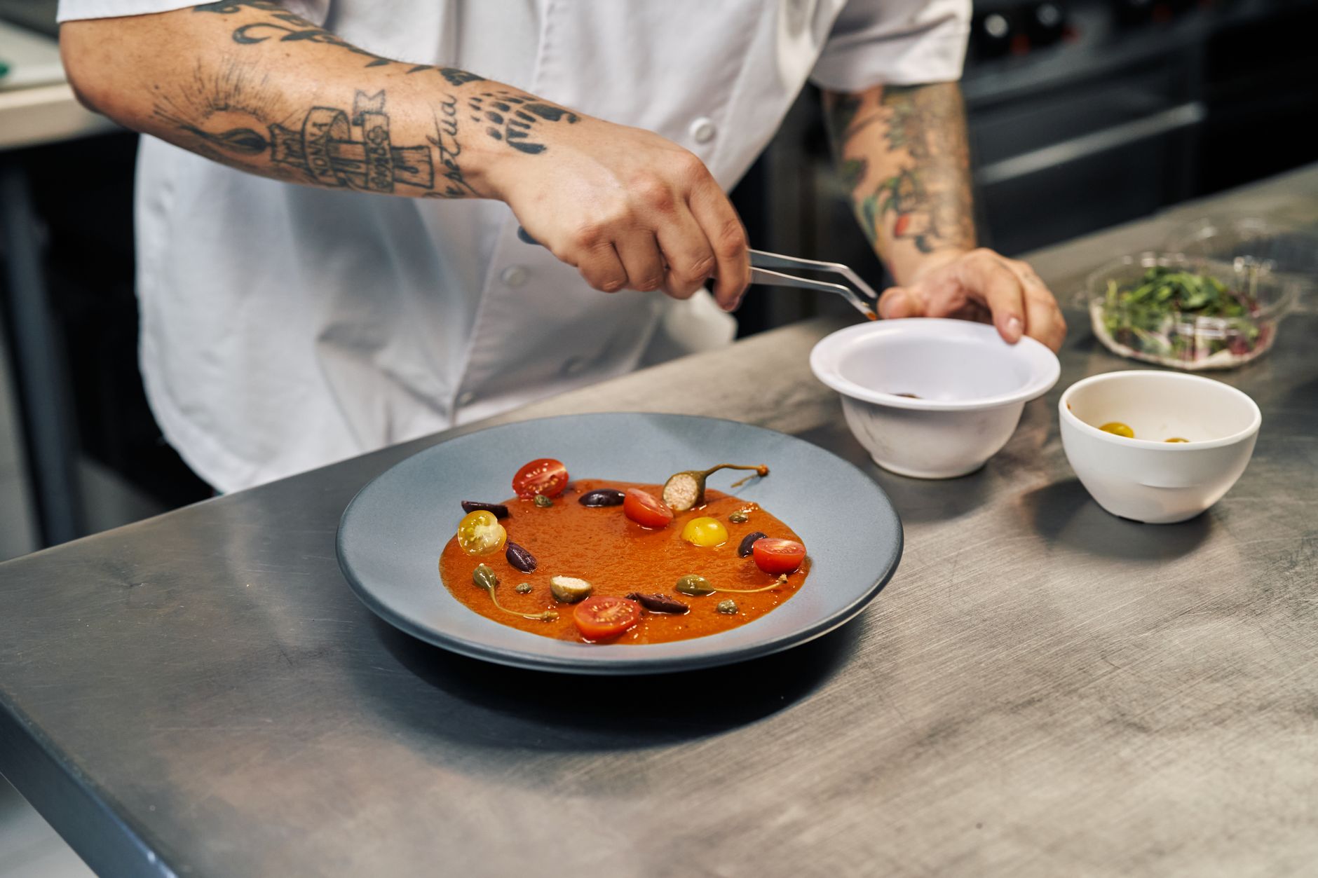 Chef preparing blended tomato soup in professional kitchen with immersion blender