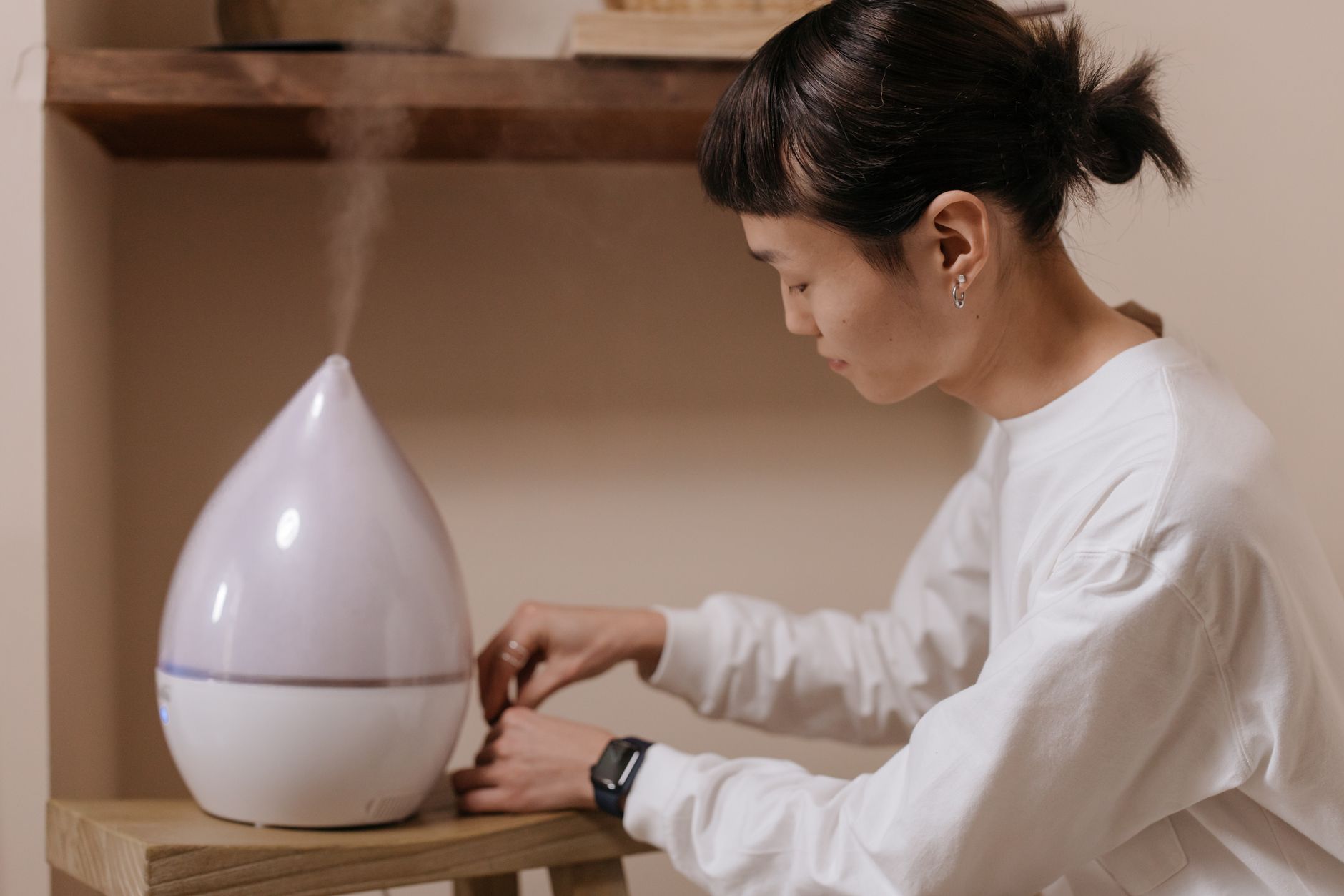 Woman adjusting a home air purifier for improved indoor air quality and fresh air circulation
