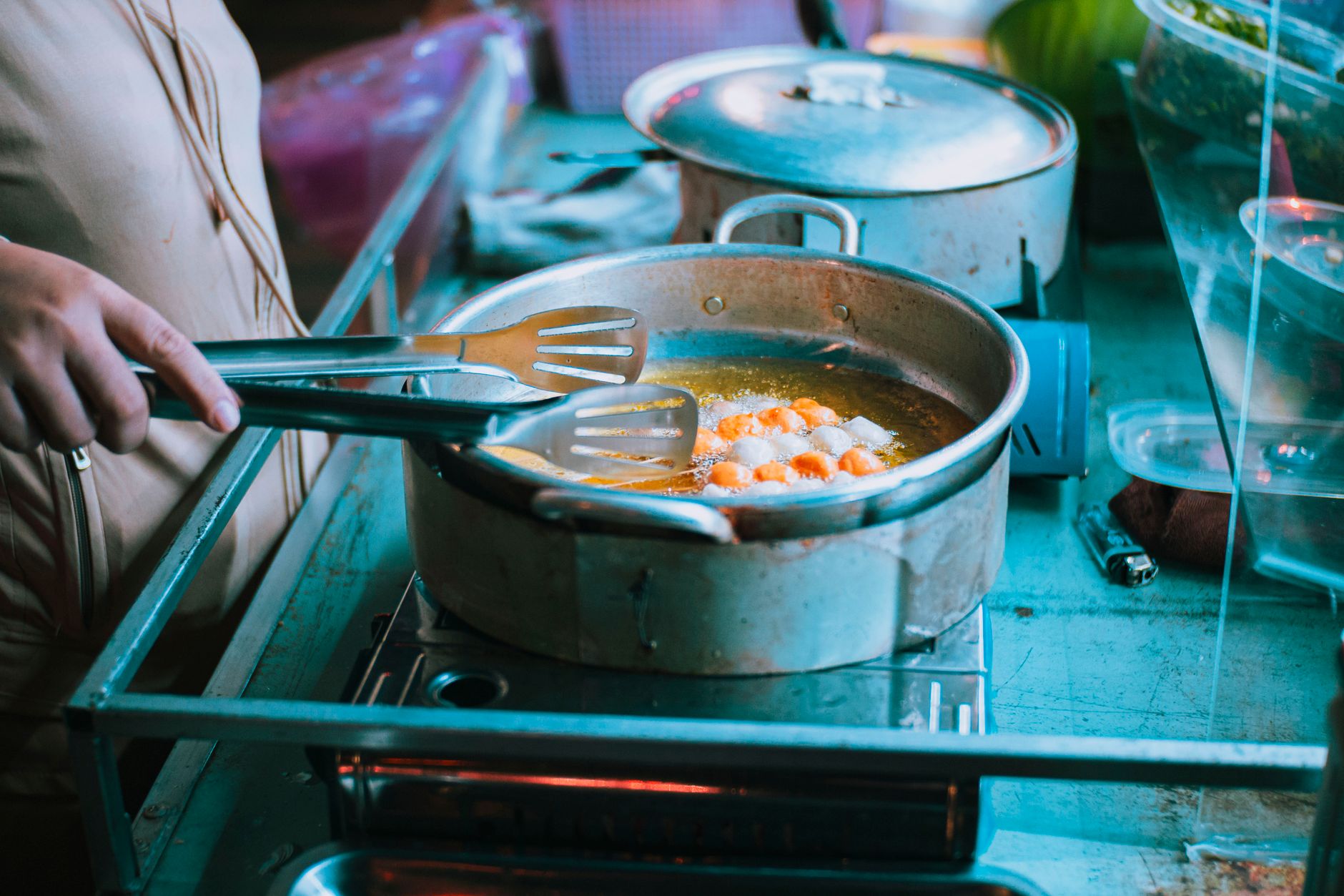 Frying food in non-stick pan with tongs on stove indoors