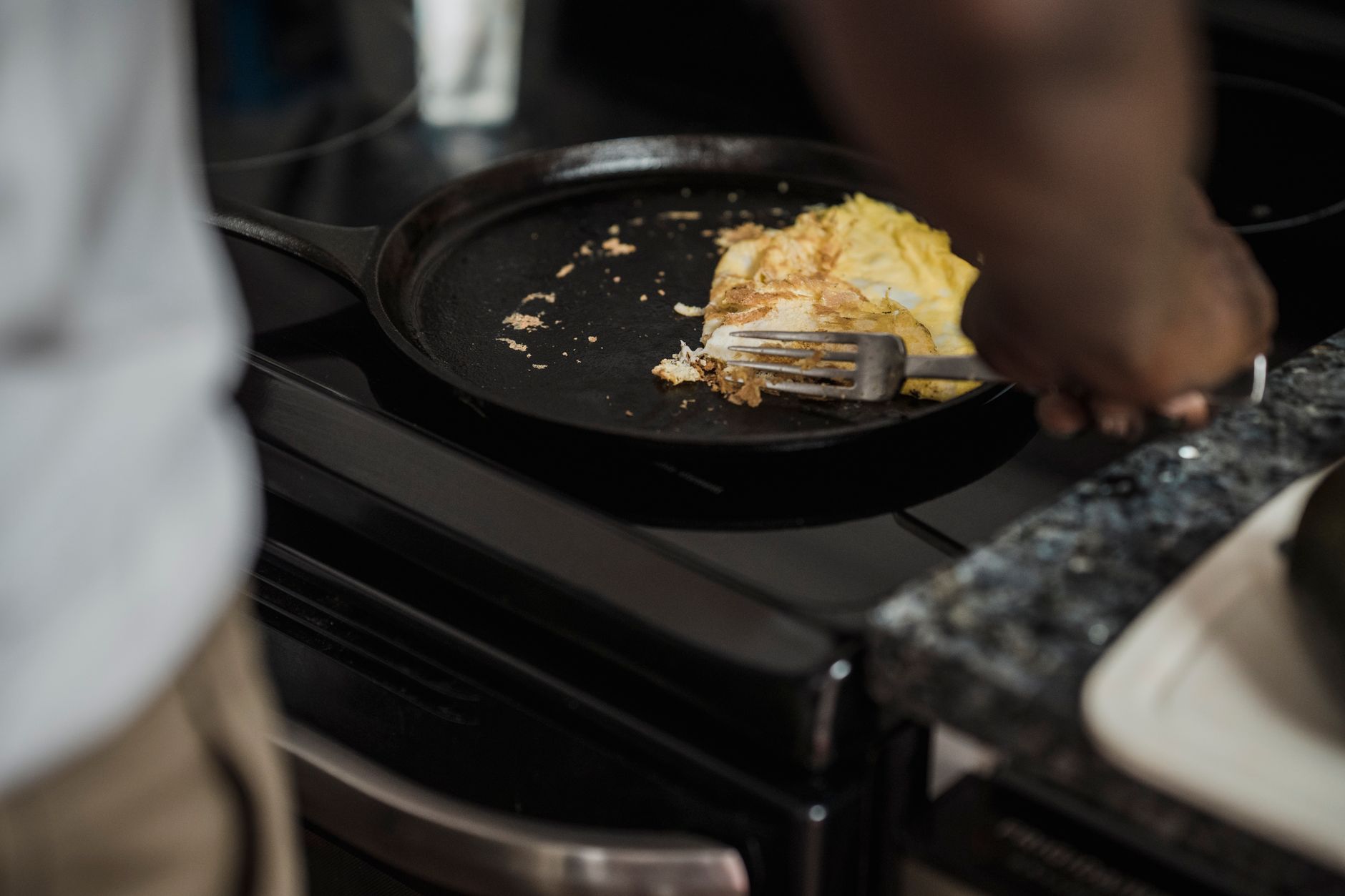 Person cooking eggs in stainless steel frying pan on stove