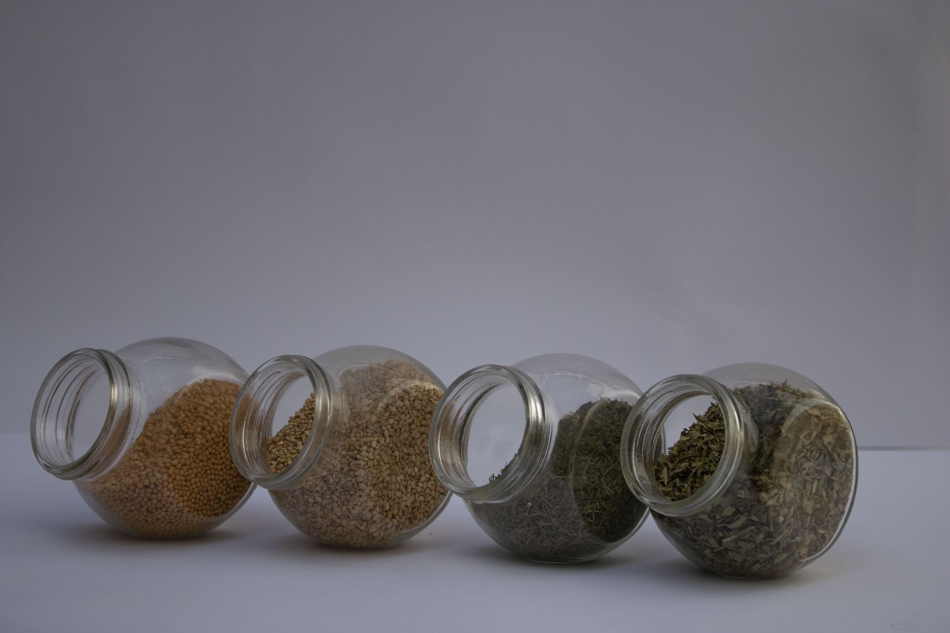 Transparent airtight glass spice storage jars with seeds and dried herbs for kitchen organisation