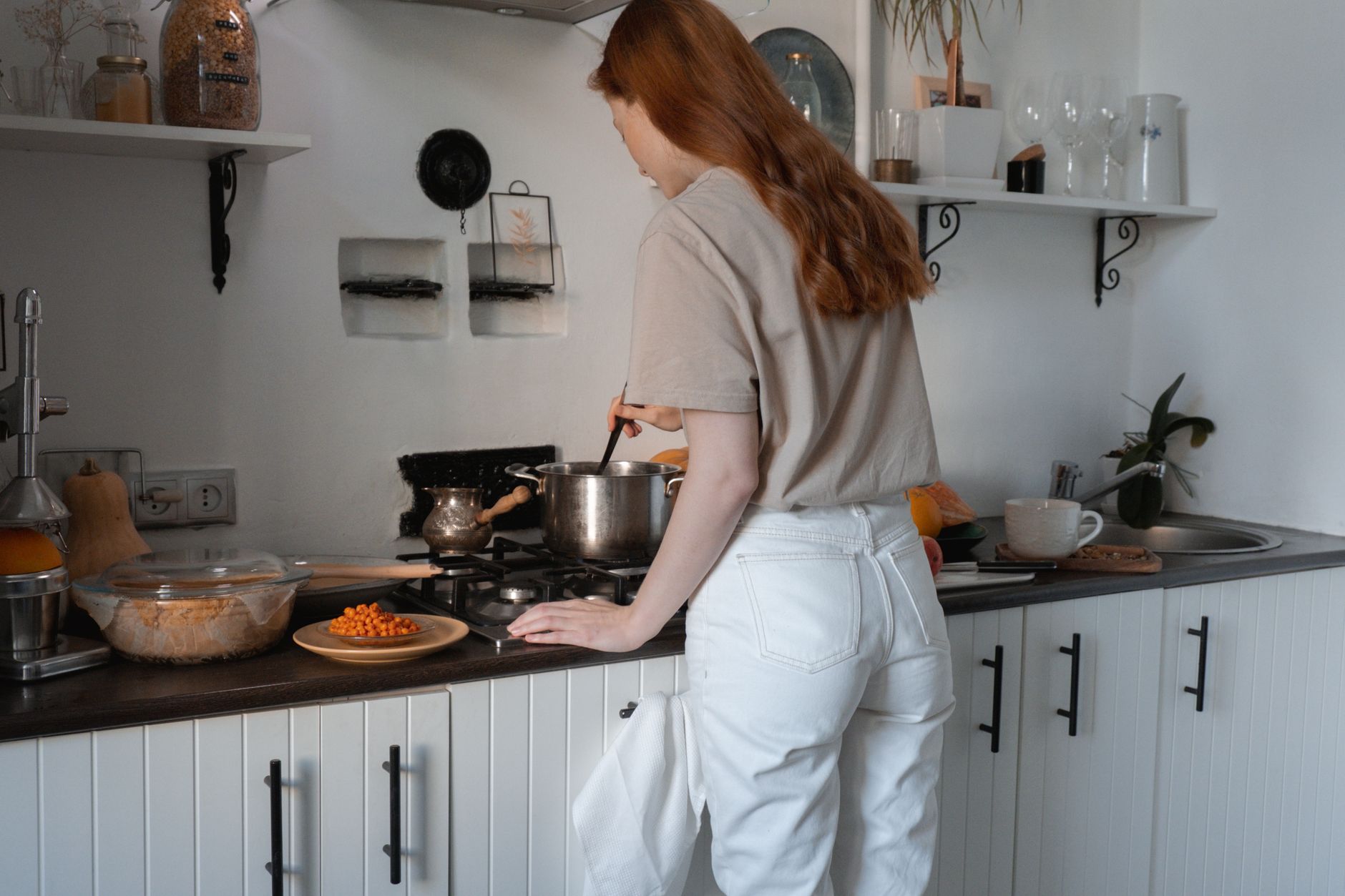 Woman cooking at home stove with quality stainless steel cookware
