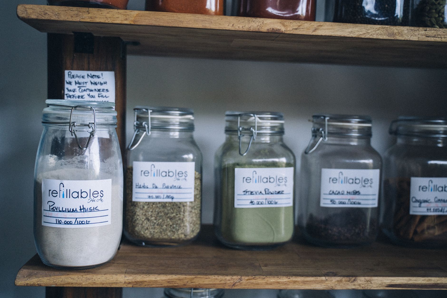 Refillable glass jars on kitchen shelf for organised food storage
