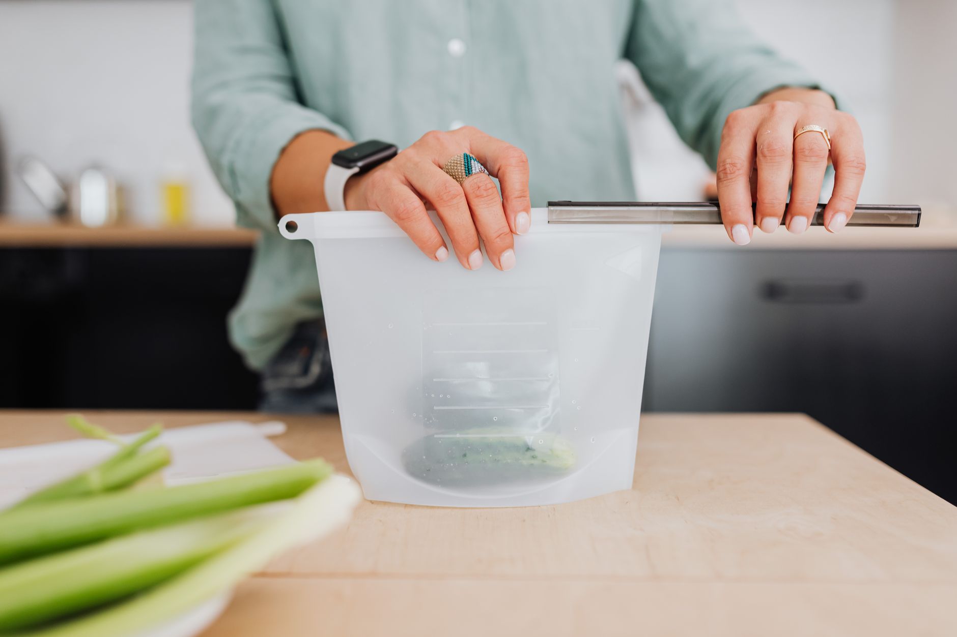 Woman sealing a food storage pouch in kitchen — similar to using the Solimo vacuum sealer for everyday kitchen needs