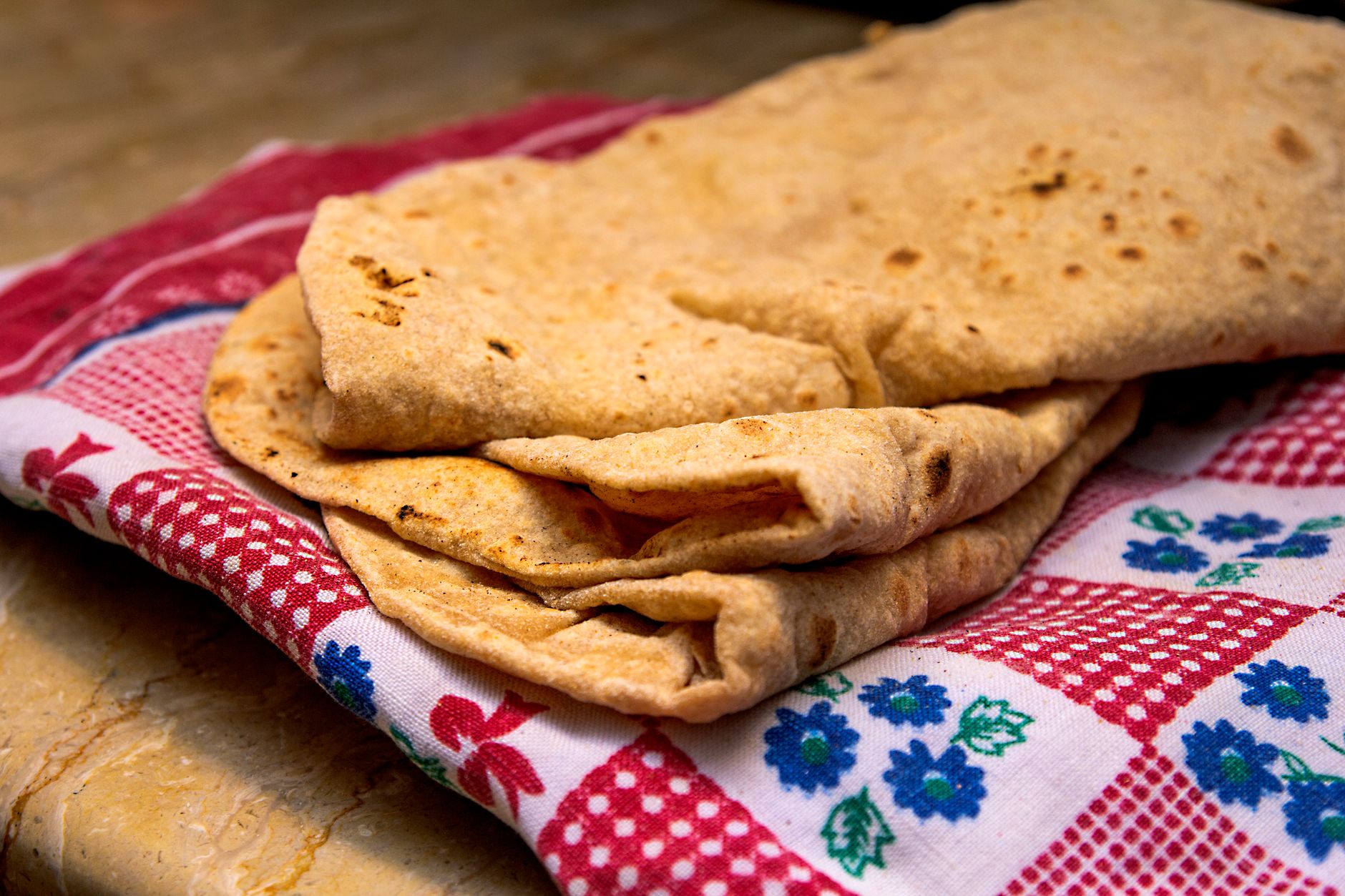 Freshly made soft chapati roti on a patterned cloth — results from a roti maker
