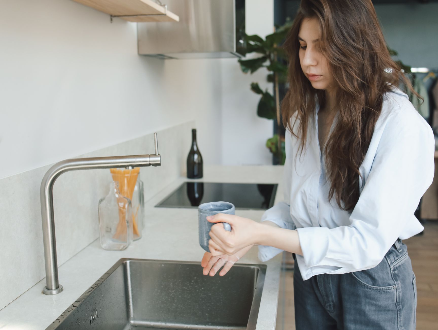 Woman in kitchen with clean water from faucet