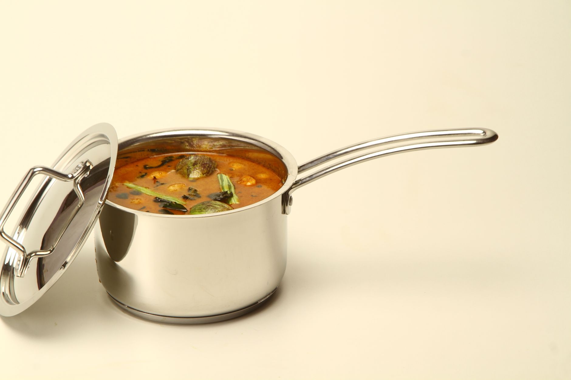 A stainless steel pot filled with flavorful Indian curry and vibrant curry leaves — the kind of dish a good pressure cooker makes effortless