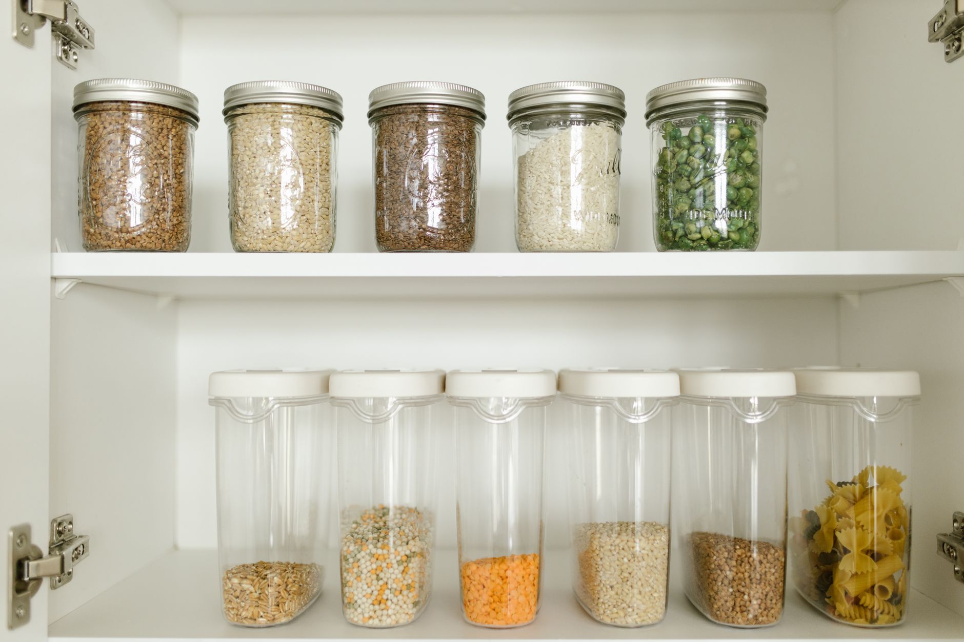 Pantry storage with grains in glass jars and food containers neatly organised on kitchen shelf in Indian home