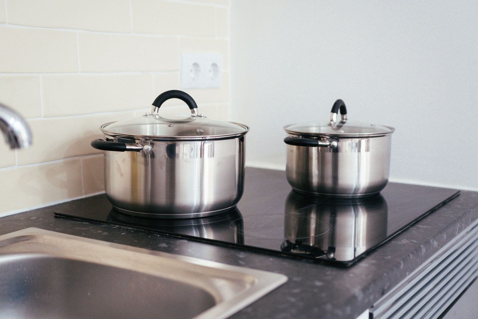 Contemporary kitchen setup with stainless steel pots on an induction stove — showing modern cookware for Indian cooking